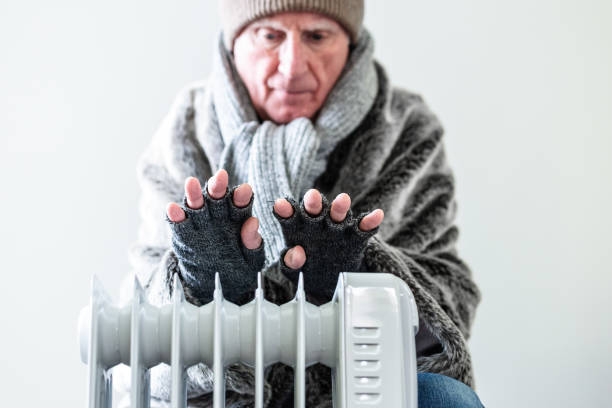 istock Cold senior man warming his hands over electric heater at home 1816805172