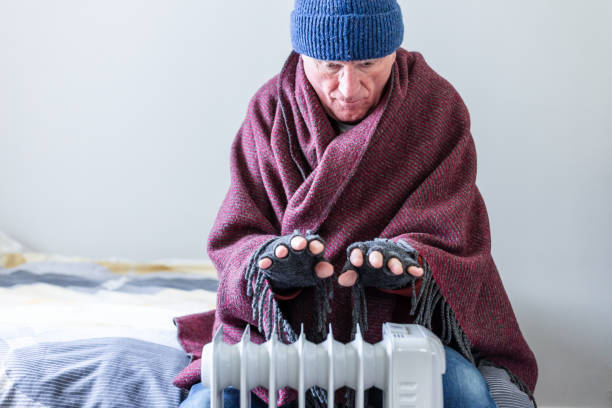 istock Cold senior man warming his hands over electric heater at home 1816805173