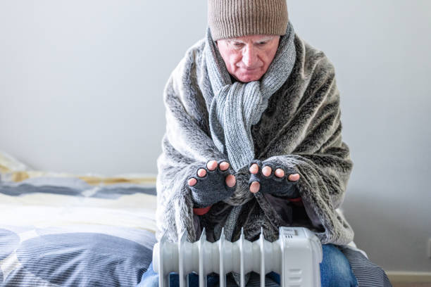 istock Cold senior man warming his hands over electric heater at home 1816805180