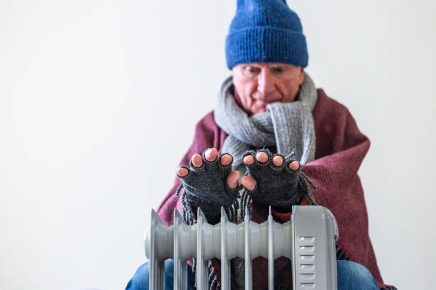 istock Cold senior man warming his hands over electric heater at home 1816805909