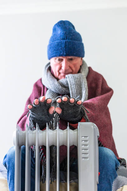 istock Cold senior man warming his hands over electric heater at home 1816806171