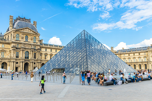 Tourists outside the glass Pyamid at the entrance of the Louvre Museum in Paris, France