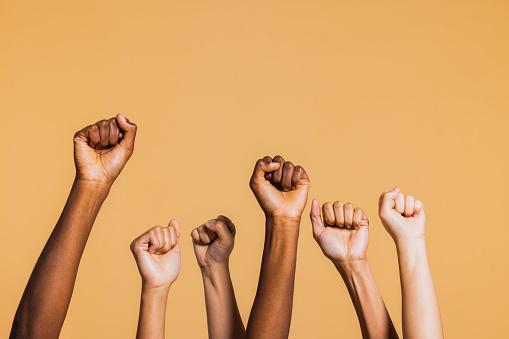 Hands raised with closed fists. Diverse coloured hands raised up with closed fist symbolizing power, determination.