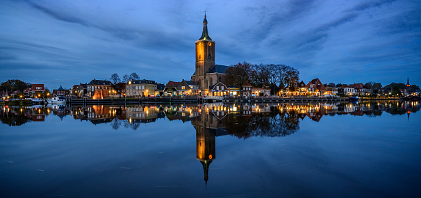 Hasselt on the banks of the Zwarte Water river during the blue hour sunset in Overijssel, The Netherlands.The skyline of the hanseatic league city is reflected in the river with the Grote of Stephanuskerk in the center.