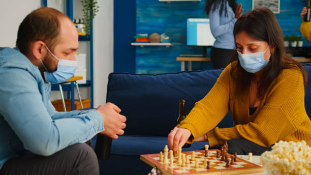 istock Friends with masks relaxing playing chess while drinking beer 1816861606