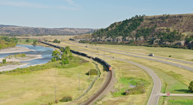Freight Train on Railway Track near Yellowstone River in Sweet Grass County, Montana in Fall - Aerial