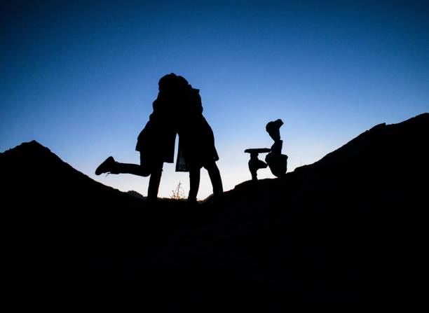 istock two people sitting in the desert on a hill at sunset 1816873903