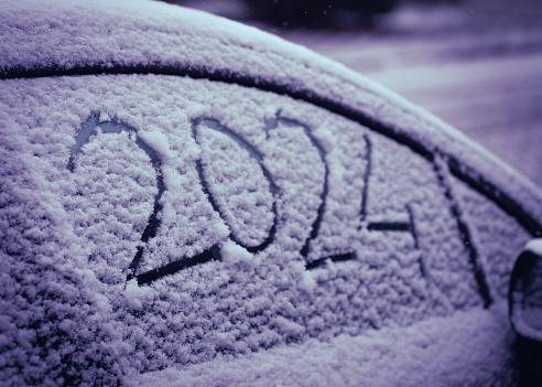 close-up snow on the car where the numbers are written 2024, textured snowy background