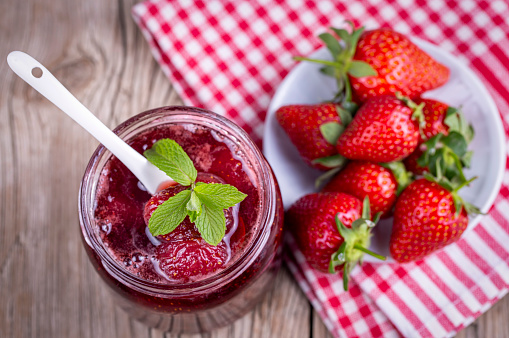 Homemade delicious strawberry jam and strawberry on a rustic wooden table