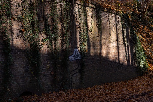 An outdoor wall featuring a mural of a vine-covered brick wall