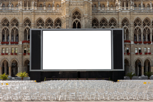 Blank screen and empty chairs for outdoor cinema in front of decorative historic building in Vienna, Austria