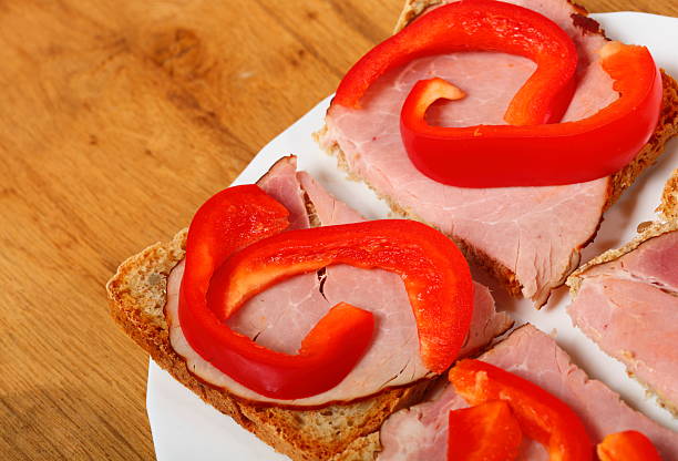 Healthy open faced sandwich with red paprika ham on wooden table background