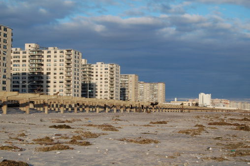 Sweeping view of the destruction of the Rockaway Park boardwalk from the shore, looking toward the towers.