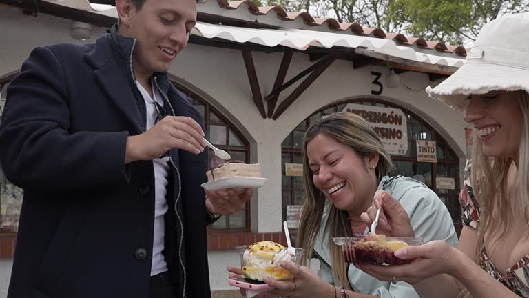 Tourist friends talking and eating dessert in the city