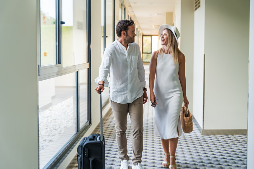 Couple with luggage walking through a luxury hotel corridor
