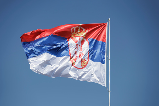 National flag of Serbia on clear blue sky