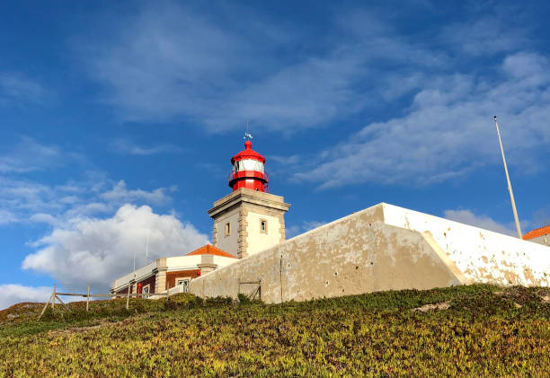 маяк на холме у мыса рока, португалия. вид на фарос, маяк, морской знак на фоне голубого неба - cabo da roca стоковые фото и изображения