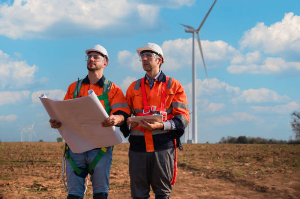 istock Two professional maintenance engineers in safety workwear using tablet and blueprint with a checklist wind turbine on windmill construction. 1816966766