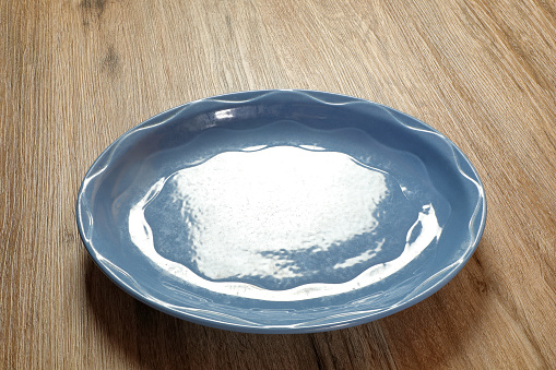 Empty plate with spoon on blue background. Top view. Kitchen Utensil.