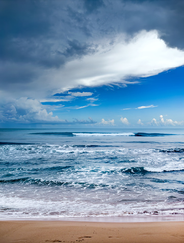 A mysterious landscape picture with wavy blue ocean and dark clouds