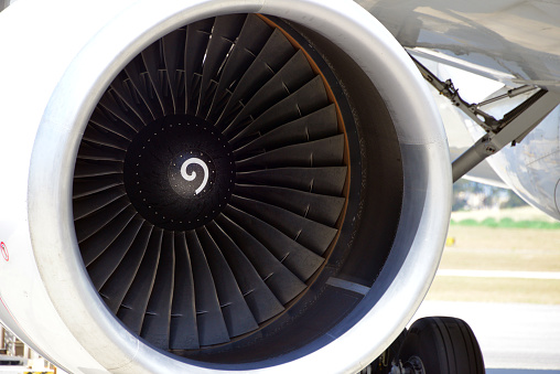 Young male aircraft maintenance mechanic inspecting and working on the private airplane jet engine in the hangar.