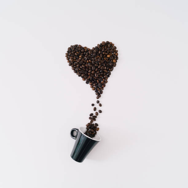 istock Creative composition with heart shape made of roasted coffee beans and coffee cup on white background. Realistic aesthetic look. Contemporary style. Minimal love concept. Unique flat lay. 1816988925
