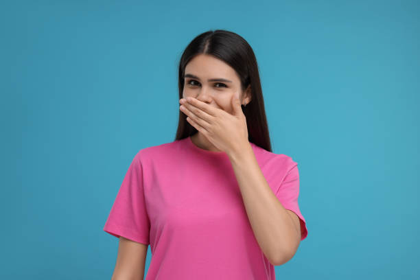istock Embarrassed woman covering mouth with hand on light blue background 1816991087
