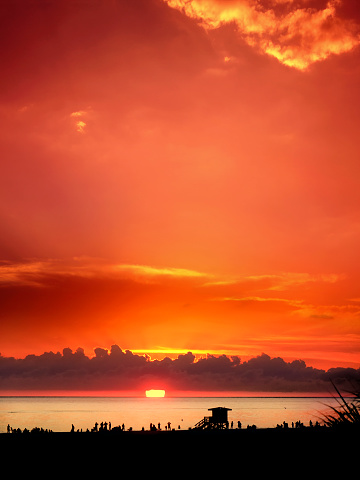 A gorgeous sunset with vibrant orange red and pink colors with sun in the horizon in Sarasota, Florida
