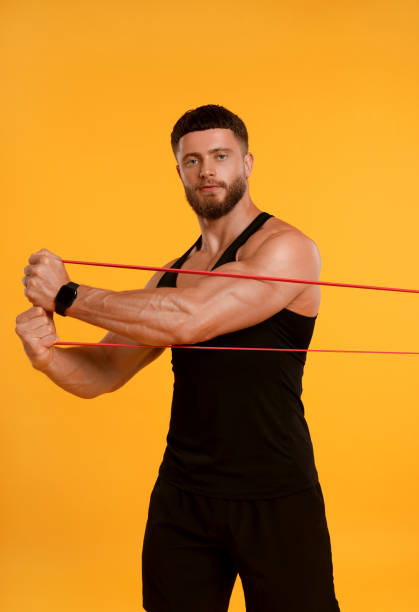 istock Young man exercising with elastic resistance band on orange background 1816993780