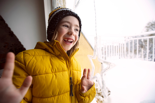 Portrait of a cute kid getting ready to go out and play in the snow. First snow of the year. Winter.