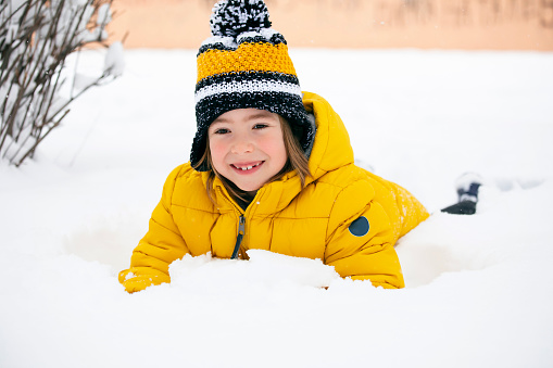 Happy little child playing in the snow. The joy of winter.