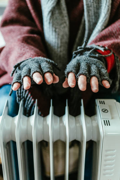 istock Cold senior man warming his hands over electric heater at home 1817031129