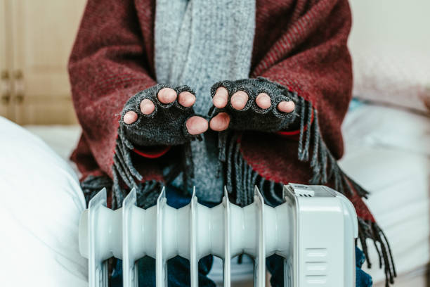 istock Cold senior man warming his hands over electric heater at home 1817031647