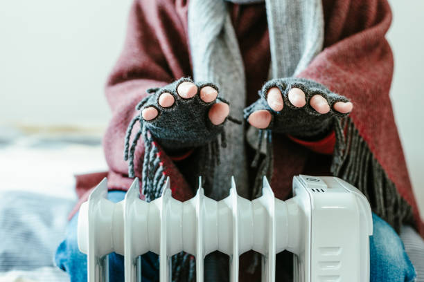 istock Cold senior man warming his hands over electric heater at home 1817032175