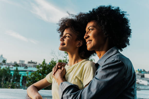 madre e hija admirando la vista juntas en el balcón - afrocaribeño fotografías e imágenes de stock