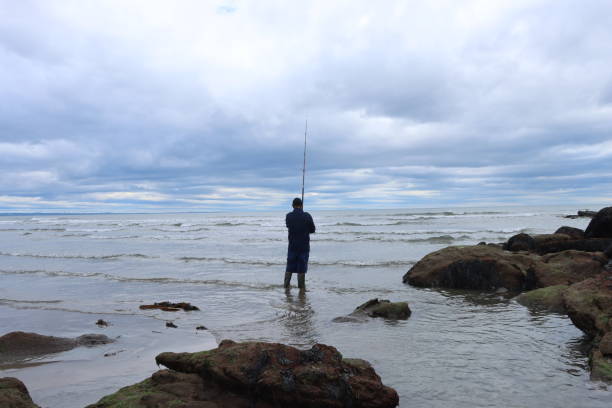 istock A man fishing with a rod on a beach 1817052273