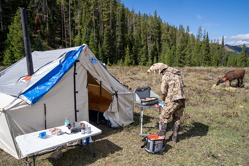 Wyoming, USA - September 23, 2023: Man makes and prepares breakfast on a camp stove at a hunting base camp (mule deer hunting) in Wyoming
