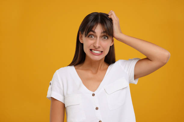 istock Embarrassed woman scratching head on orange background 1817074649