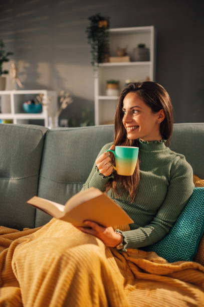istock A young woman is reading book at cozy home and drinking coffee. 1817101489