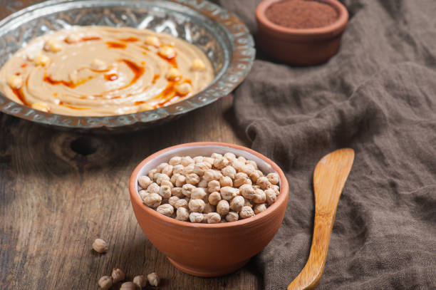 foto de ángulo alto de un cuenco de garbanzos crudos con un plato de humus en el fondo - lentil dinner holiday mediterranean cuisine fotografías e imágenes de stock