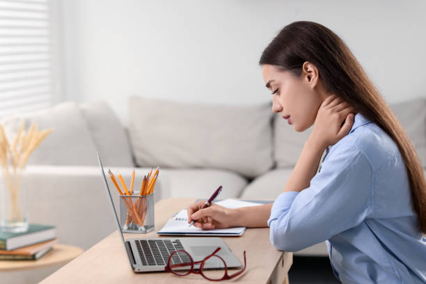istock Young woman suffering from neck pain while working at table in office 1817109455
