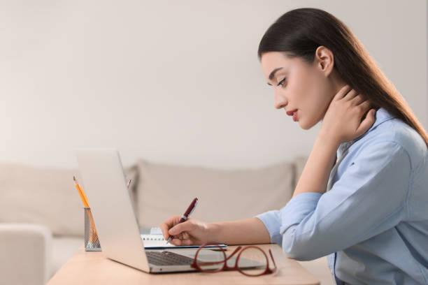 istock Young woman suffering from neck pain while working at table in office 1817109474