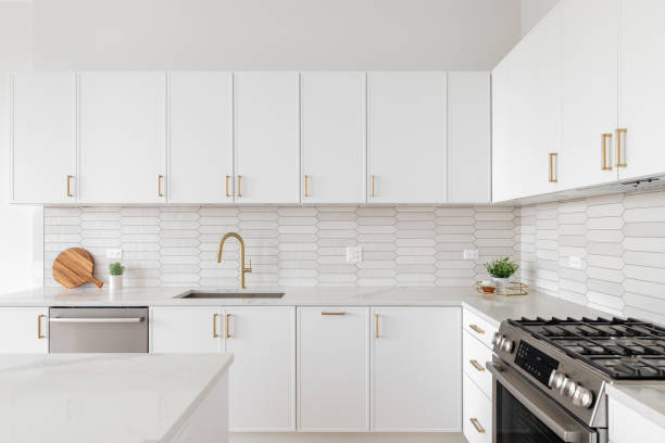 istock A kitchen detail with white cabinets, picket tile backsplash, and a gold faucet. 1817112268
