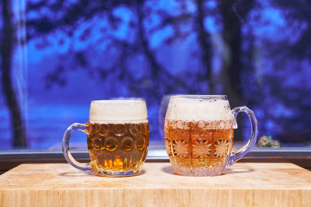 Two pints of lager beer pilsner type form Czech Republic. Two pints of lager beer pilsner type form Czech Republic in the traditional czech style mugs in front of window during the cold winter evening. Special kind of beer is traditional drink for Christmas. former czechoslovakia stock pictures, royalty-free photos & images