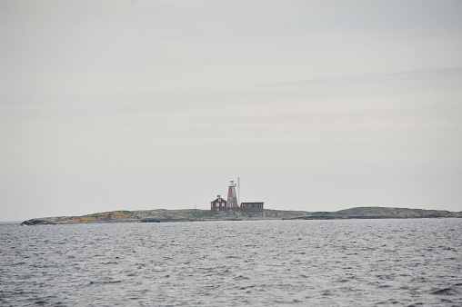 A lighthouse on a small island in the Baltic Sea, captured from a distance on a cloudy day