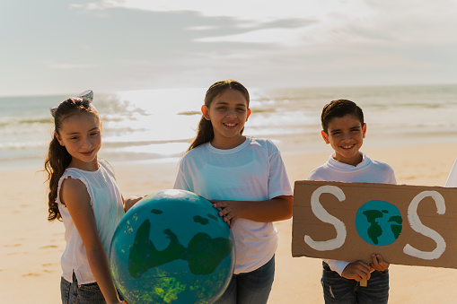 Portrait of children protesting to save planet Earth on the beach