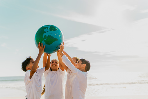 Children holding a planet on the beach