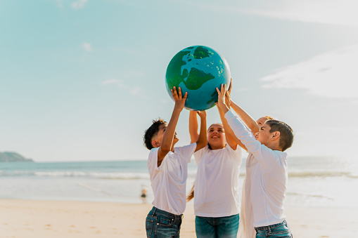 Children holding a planet on the beach