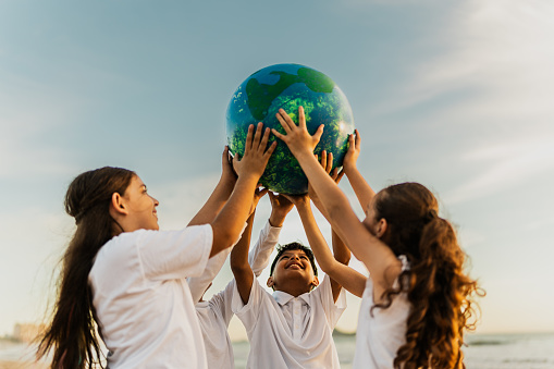 Children holding a planet on the beach