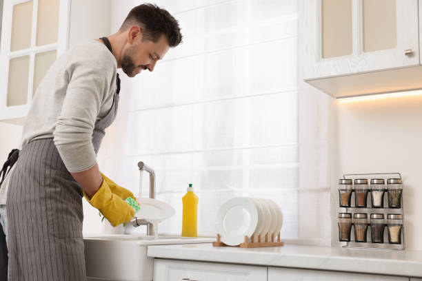 istock Man washing plate above sink in kitchen 1817139589